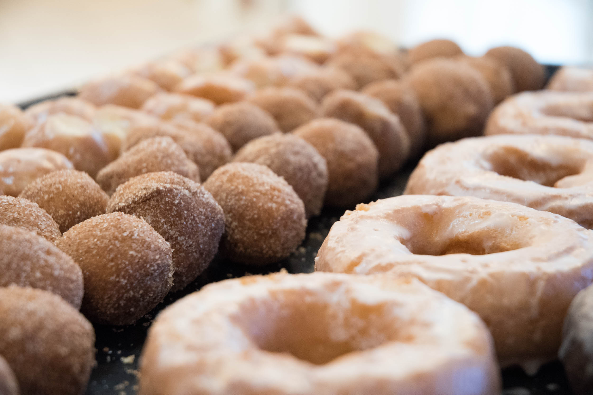 Sugar dusted donut holes and glazed donuts lined up on a platter